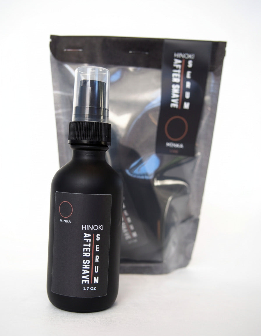A black bottle of Hinoki After Shave Serum with a spray nozzle, in front of its packaging.