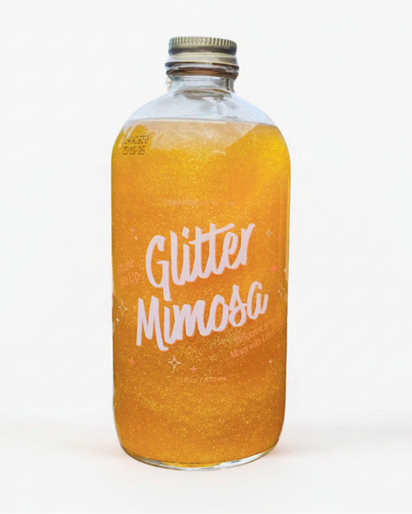 A bottle labeled 'Glitter Mimosa' with a golden-colored liquid inside, indicating a sparkling drink mix with edible glitter.
