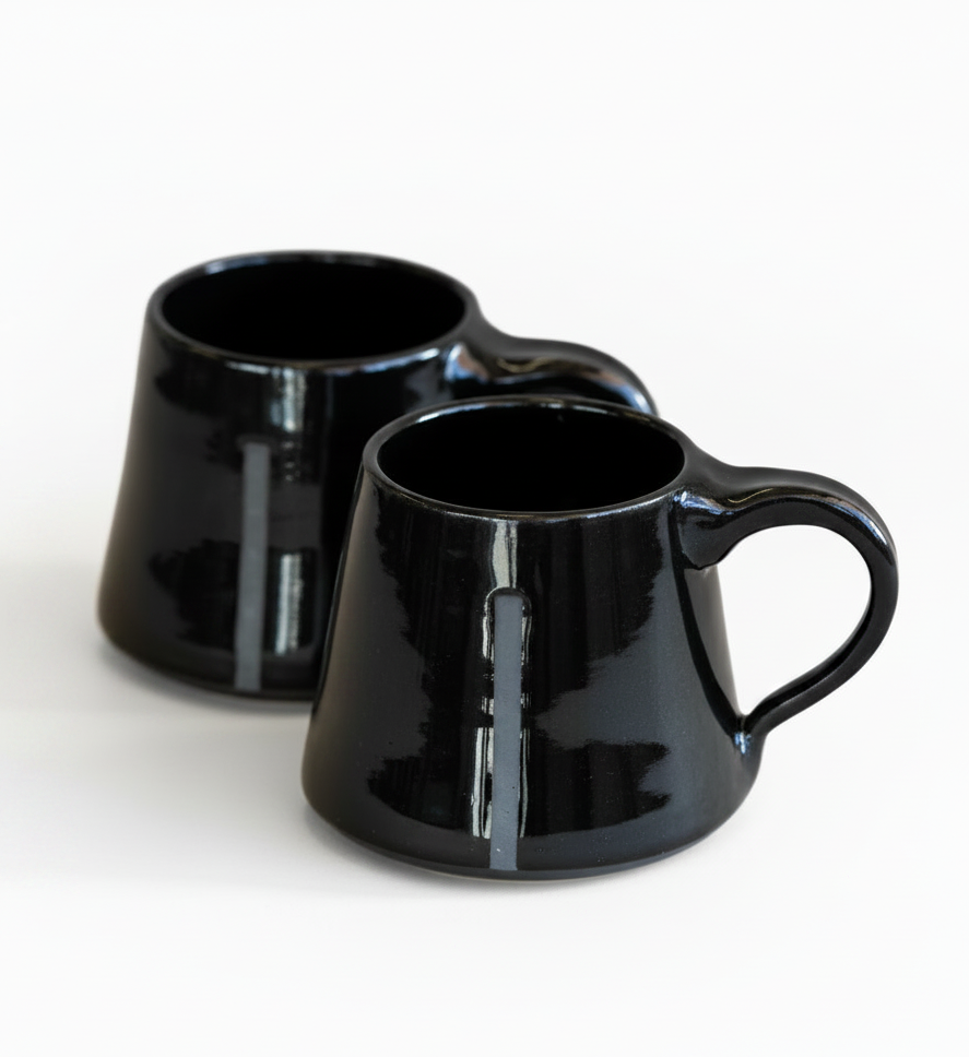 Two black ceramic mugs on a white background
