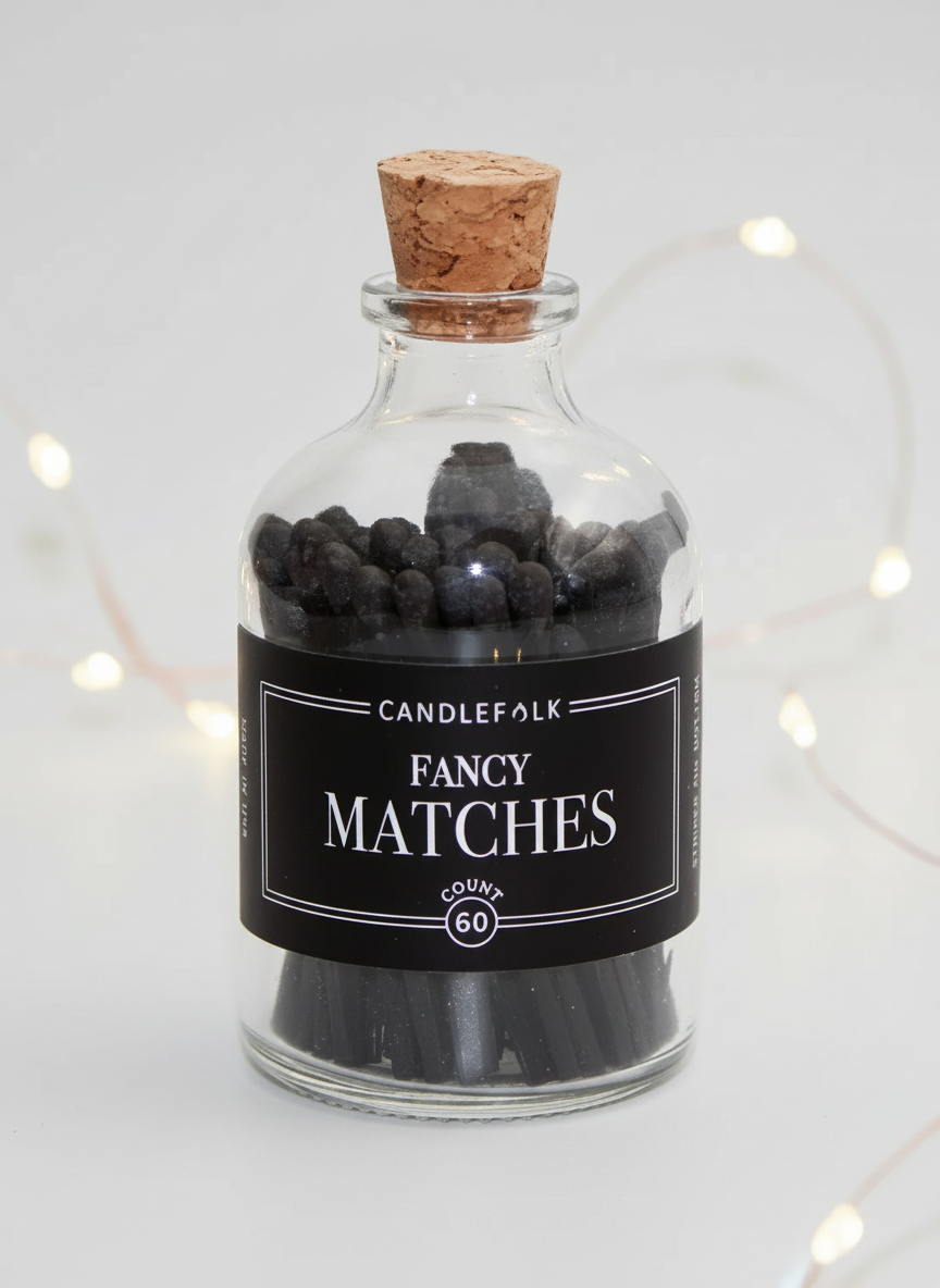 Glass bottle with cork lid containing black matches labeled 'Candlefolk Fancy Matches' on a white background.