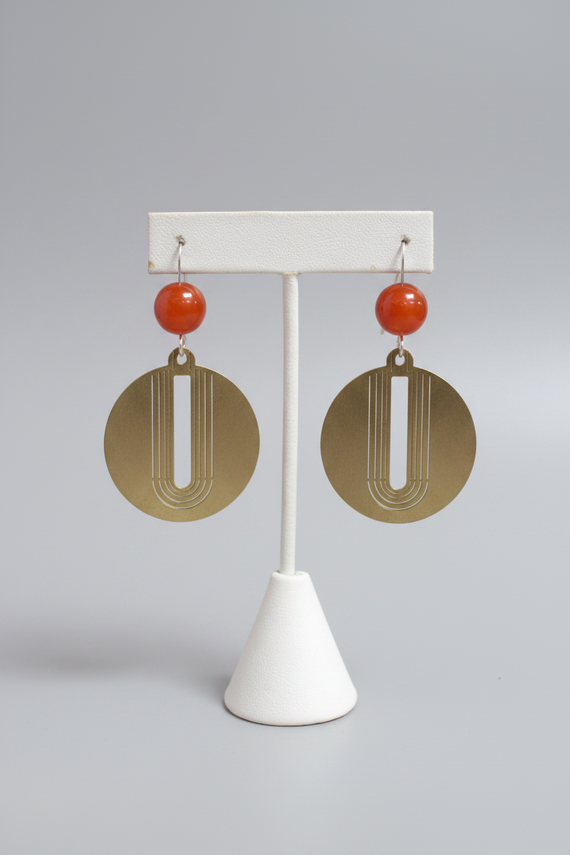 Pair of earrings on a white stand against a wooden background