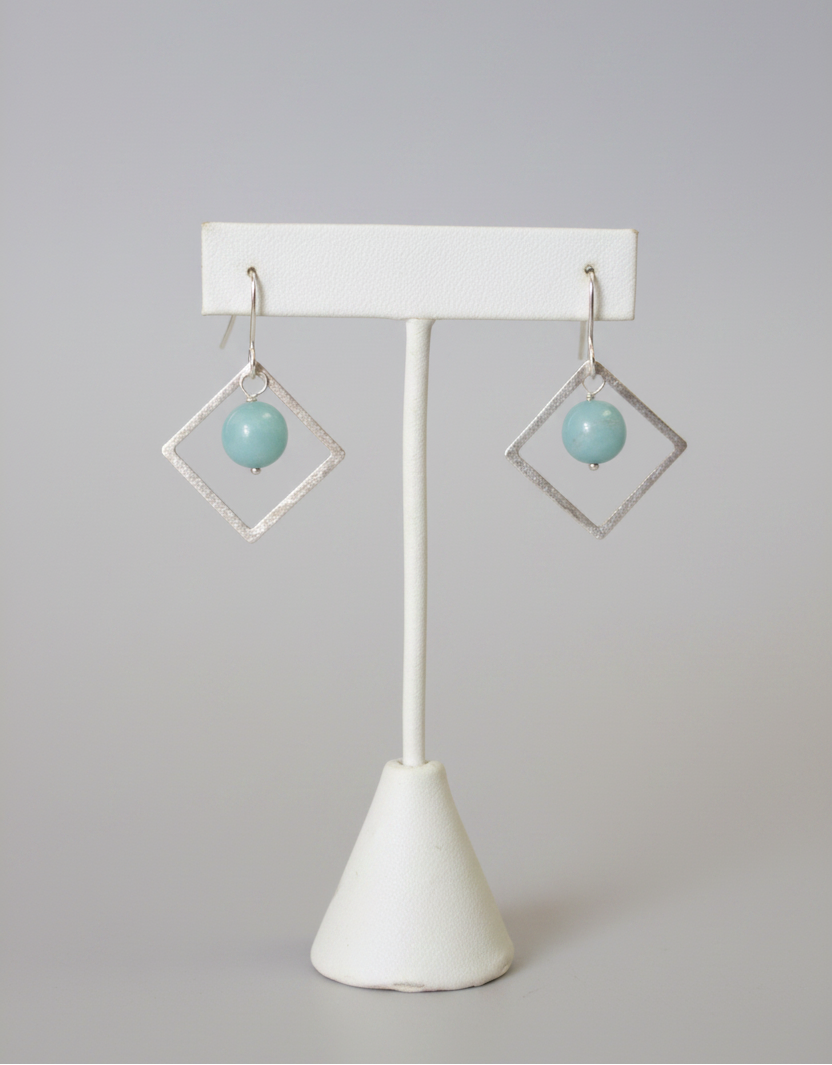 Pair of earrings on a white stand with a plain background