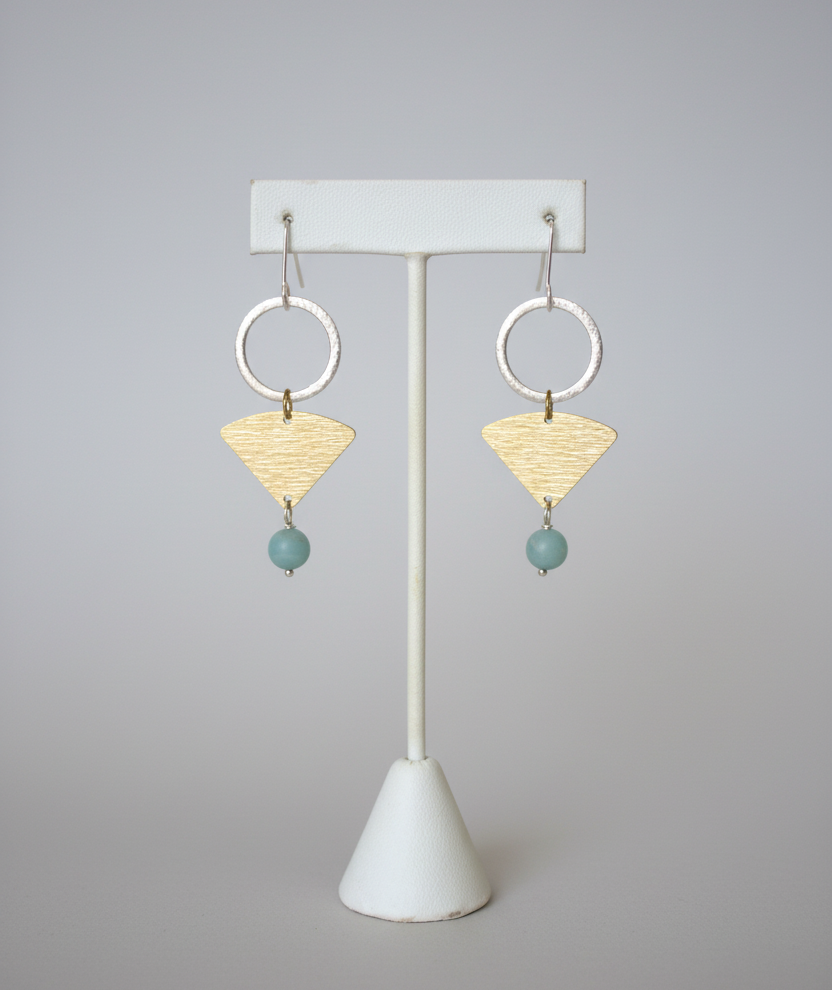 Pair of earrings on a white stand with a plain background