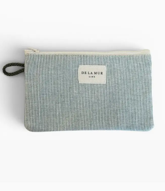 A small zippered pouch with a blue and white vertical stripe pattern, featuring a cream-colored brand label that reads 'DE LA MUR LONDON' and a dark green braided loop handle on the left, set against a plain white background.