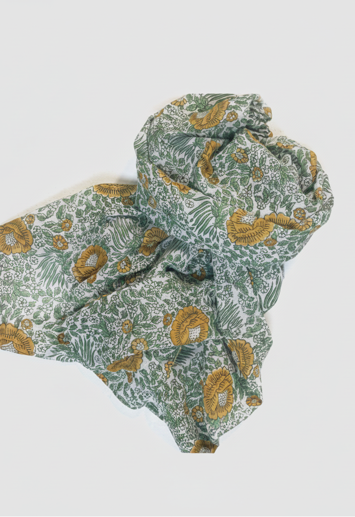 A crumpled fabric scarf or throw with a botanical pattern in sage green, olive, and mustard yellow on a white background, photographed on a clean white studio background.