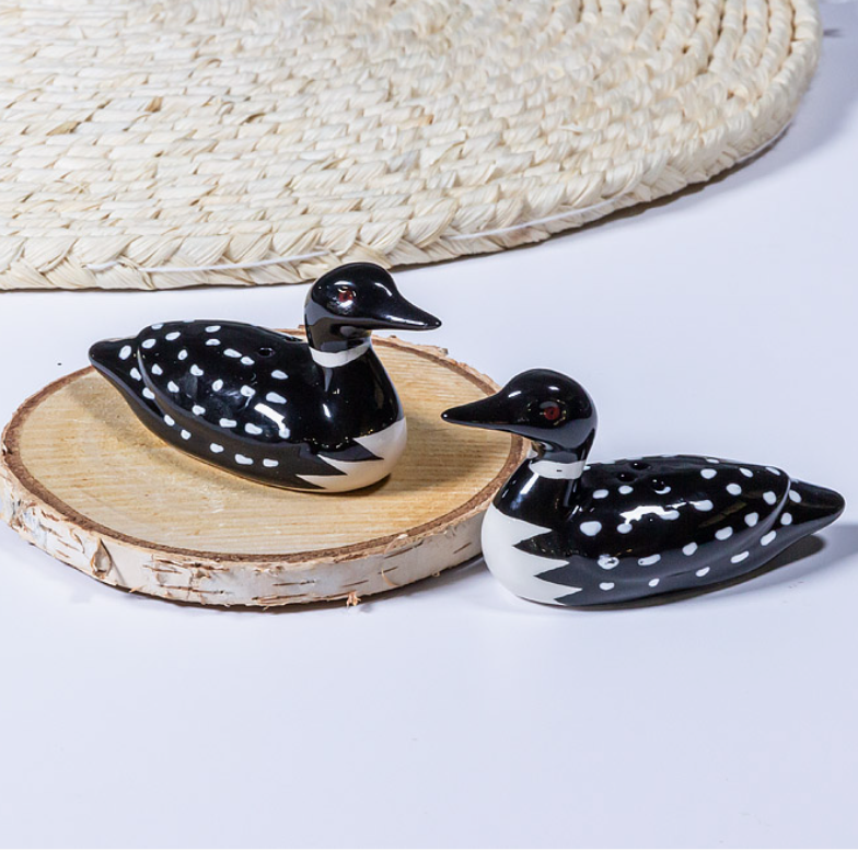 Two ceramic duck figurines with black and white patterns on a wooden surface.