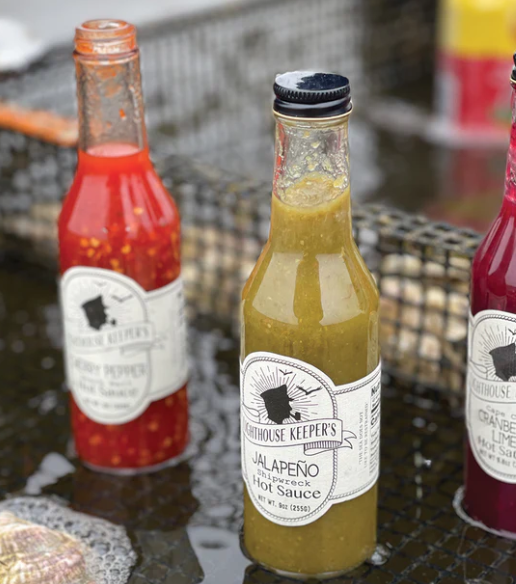 Three bottles of Gathouse Keeper's hot sauce on a metal surface.