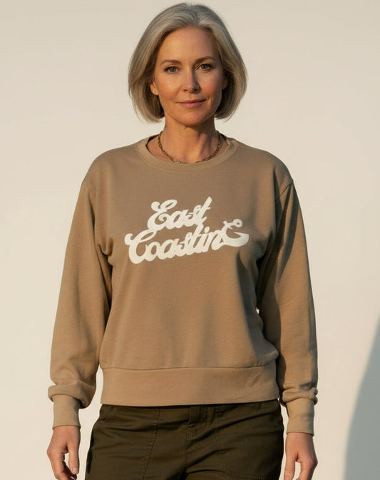 Person wearing a brown sweatshirt with 'East Coasting' text on a plain background