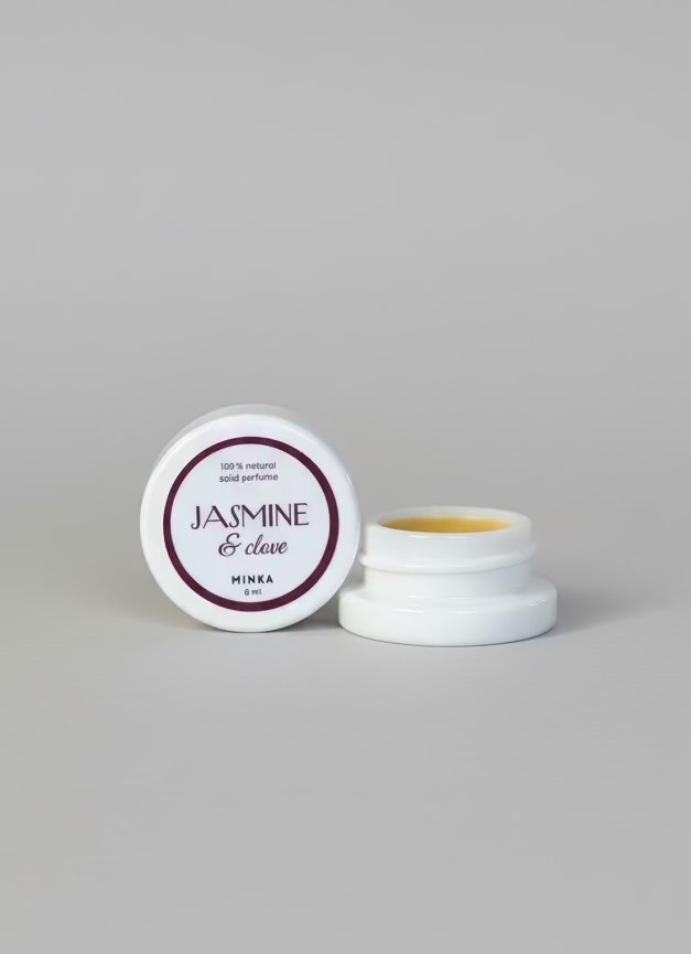 Two small containers of cream with 'Jasmine & Dove' label on a reflective surface.