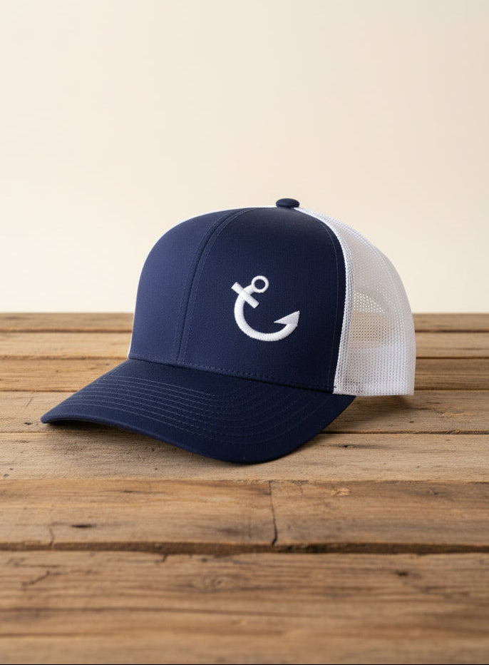 Navy blue cap with white mesh back and anchor logo on a wooden surface