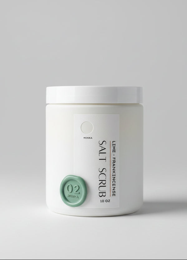 White container of salt scrub with 'Lime Frankincense' flavor on a wooden surface