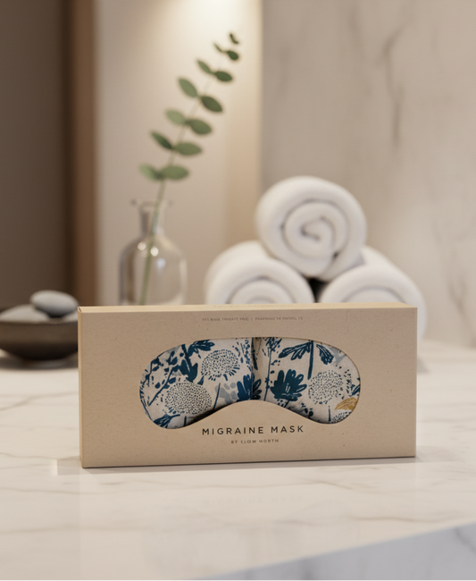 Migraine mask with floral design in a beige box on a wooden surface.