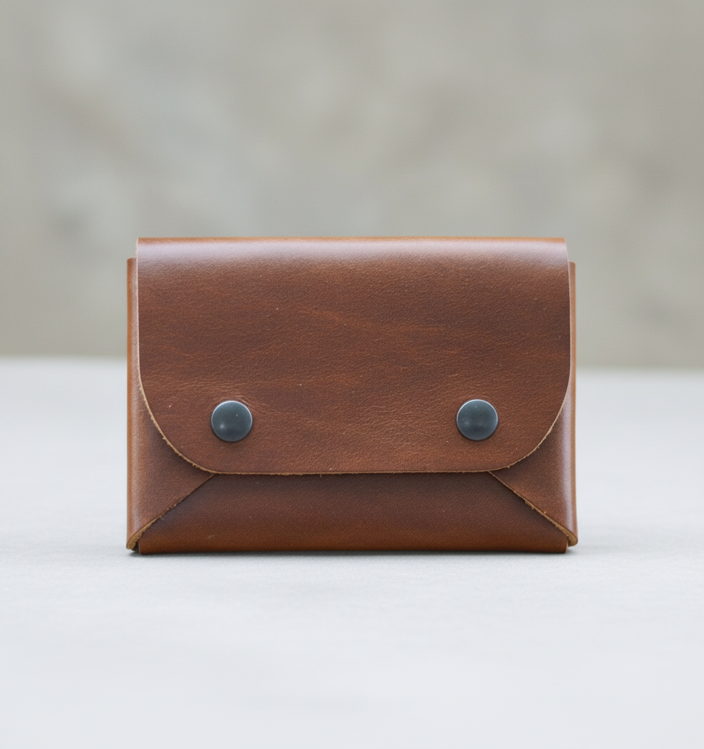 Brown leather wallet with metal buttons on a wooden surface with rocks