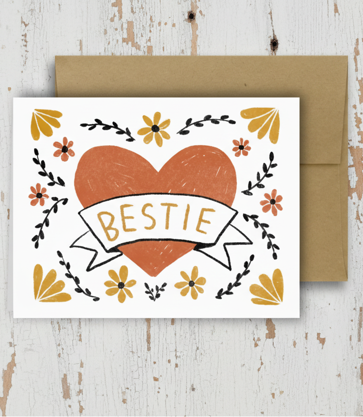 Card with heart design and 'BESTIE' text on a wooden surface