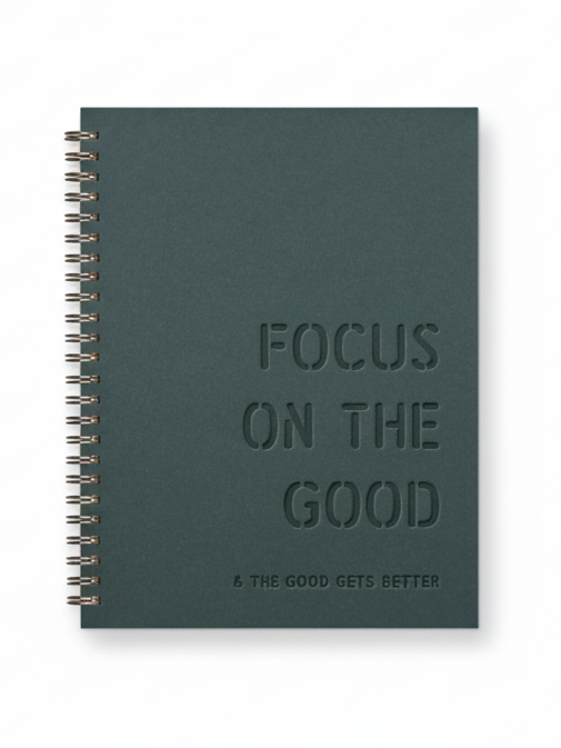Green notebook with 'Focus on the Good' text on a white background
