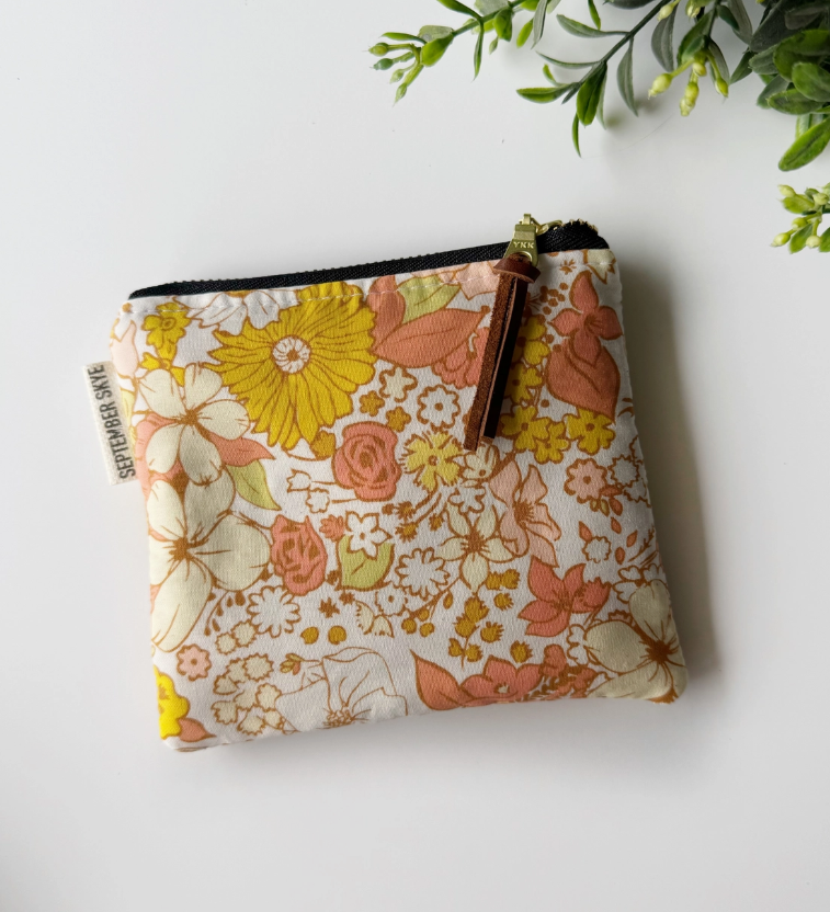 Floral patterned pouch with a brown strap on a white background