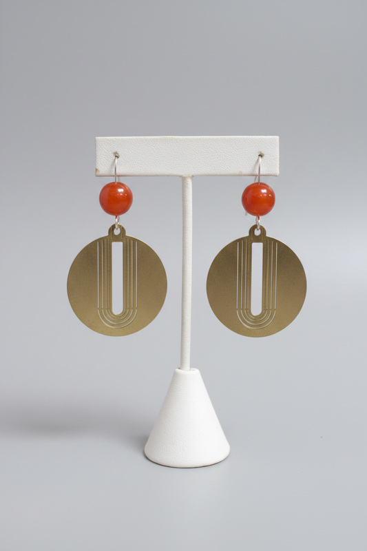 Pair of earrings on a white stand against a wooden background