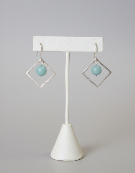Pair of earrings on a white stand with a plain background