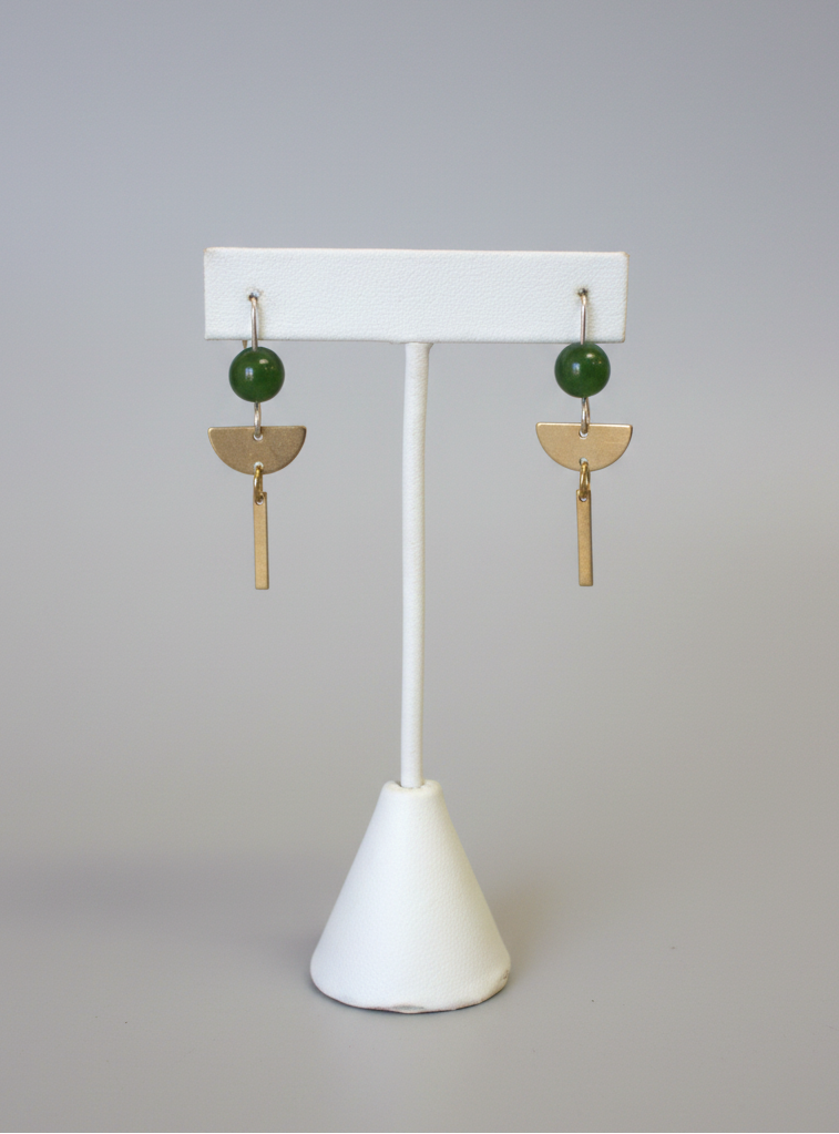 Pair of earrings on a white stand with a plain background