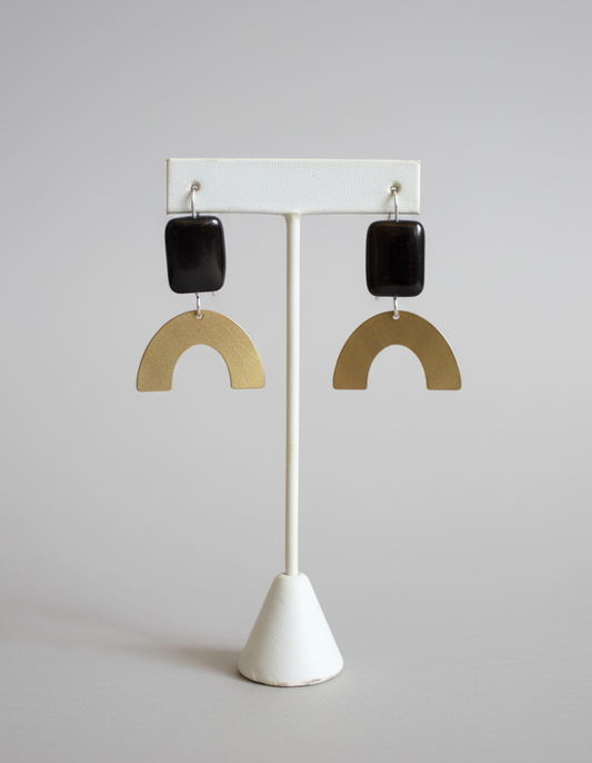 Pair of earrings on a white stand against a wooden background