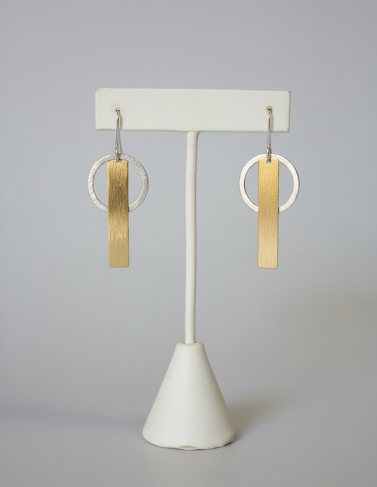 Pair of earrings on a white stand against a plain background