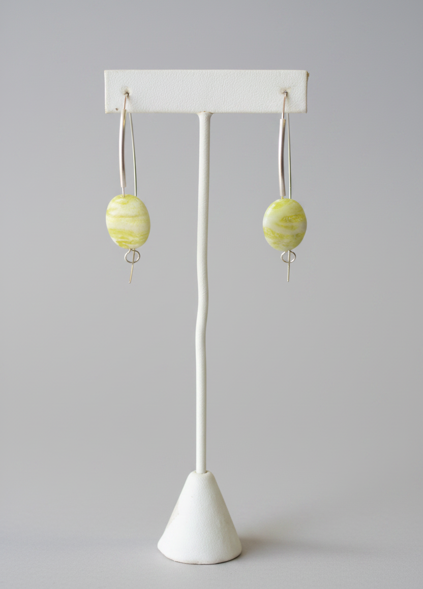 Earrings with marbled design on a white stand against a plain background