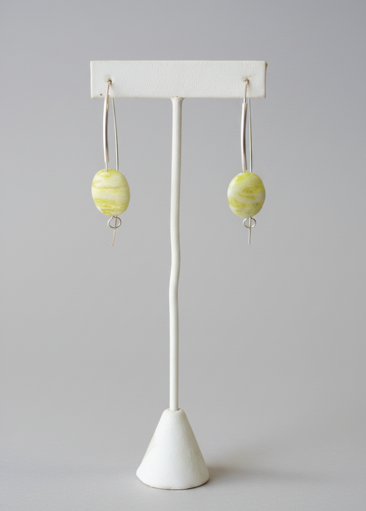 Earrings with marbled design on a white stand against a plain background