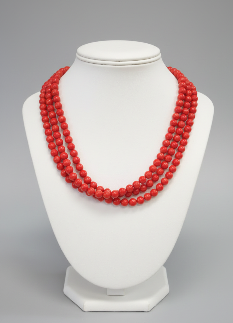 Red beaded necklace on a brown stand with a wooden background