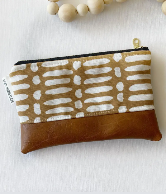 Small pouch with brown patterned top and brown leather bottom on a white background