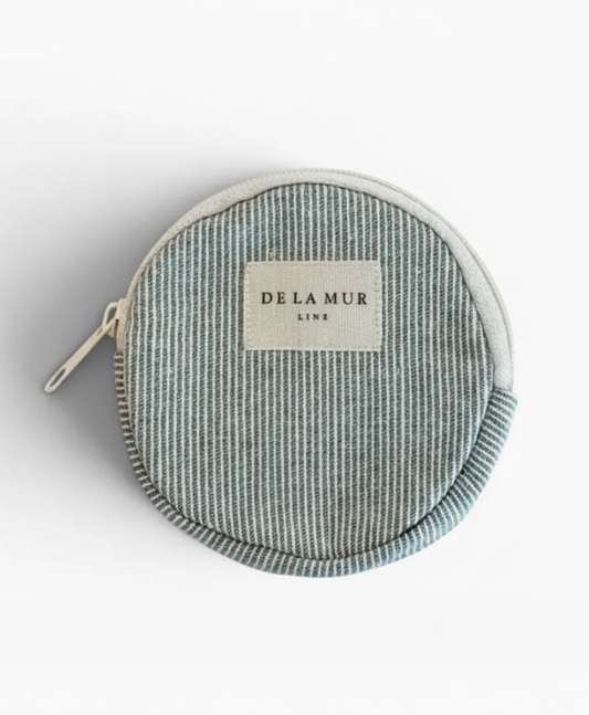 A round zippered pouch by Delamur Line featuring a vertical striped pattern in light blue and white, with a cream-colored brand label on the front.