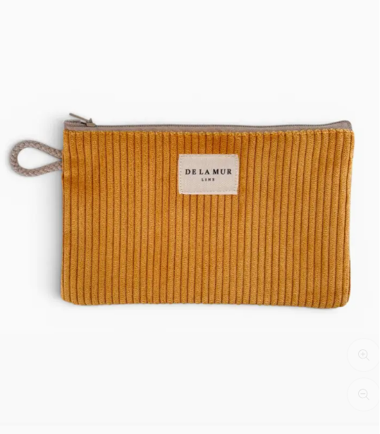 A mustard yellow corduroy pouch with a silver zipper and a beige fabric loop handle, featuring a cream-colored 'DE LA MUR LONDON' label on the front.