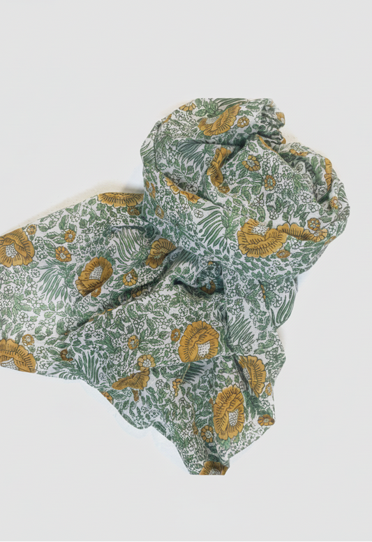 A crumpled fabric scarf or throw with a botanical pattern in sage green, olive, and mustard yellow on a white background, photographed on a clean white studio background.