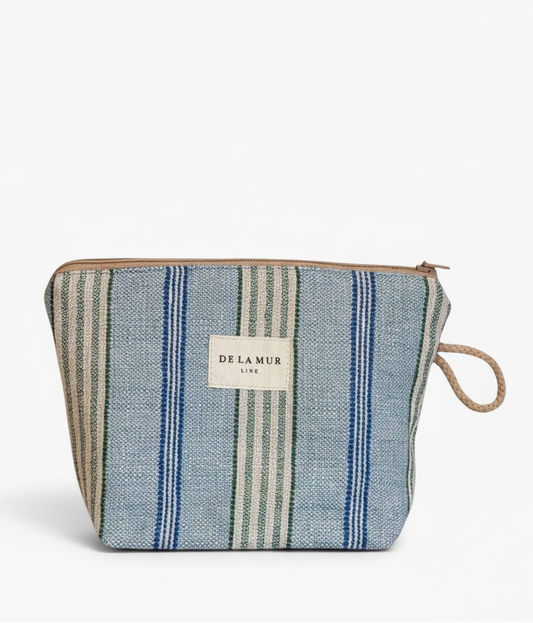 A zippered pouch featuring a blue, green, and beige striped woven fabric body, a beige brand label on the front, and a natural jute loop handle, set against a plain white background.