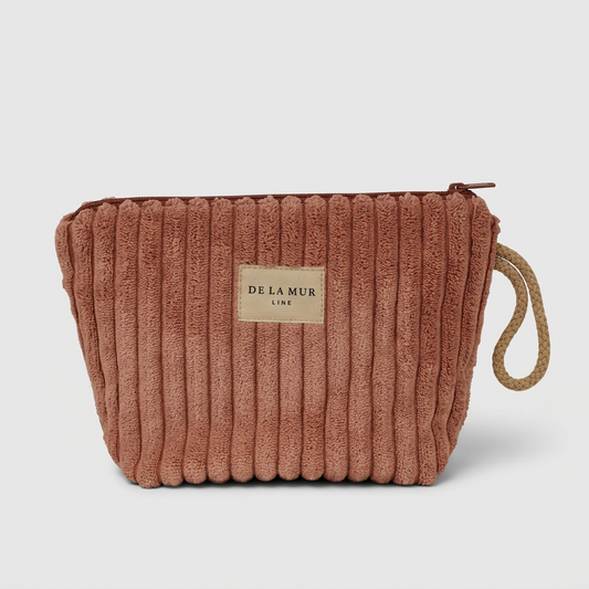 A dusty rose corduroy cosmetic pouch with a beige fabric brand label reading 'DELA MUR LINE' and a natural jute loop handle, shown on a light gray background.
