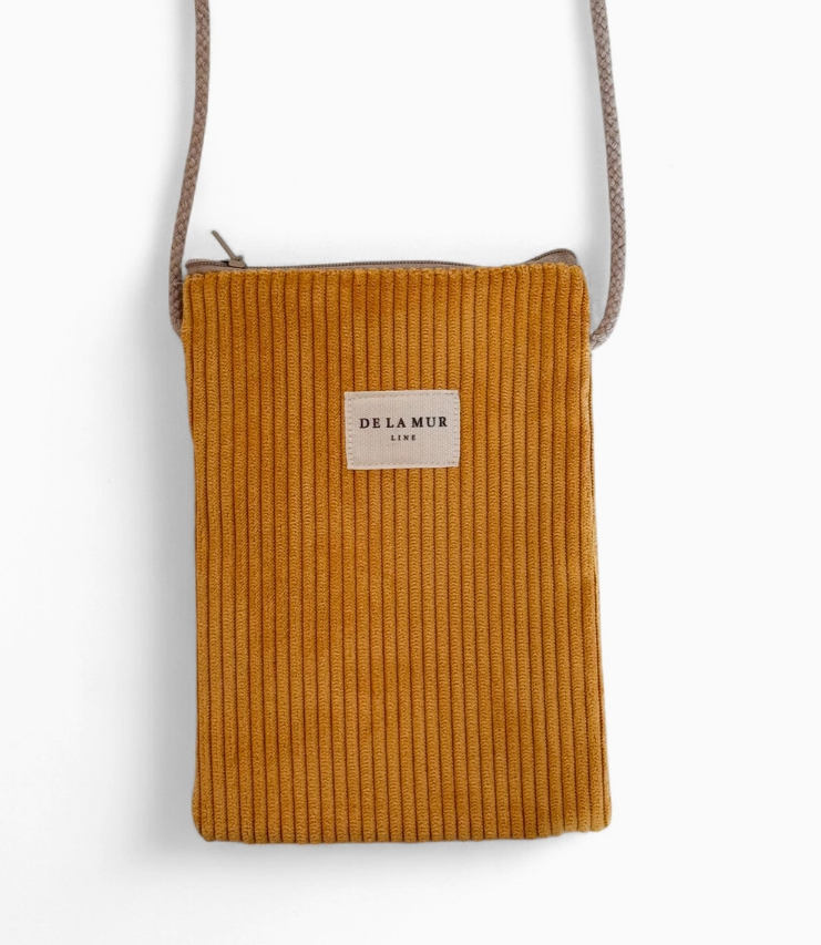 A mustard yellow corduroy crossbody bag with a beige brand label reading 'DE LA MAR' and a matching beige braided strap, shown against a plain white background.