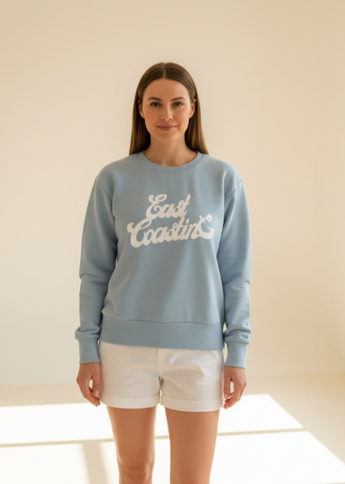 Woman wearing a light blue sweatshirt with 'Good Lovin'' text, standing against a plain background