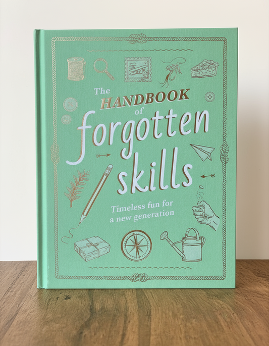 Book titled 'The Handbook of Forgotten Skills' on a wooden surface with a blurred background