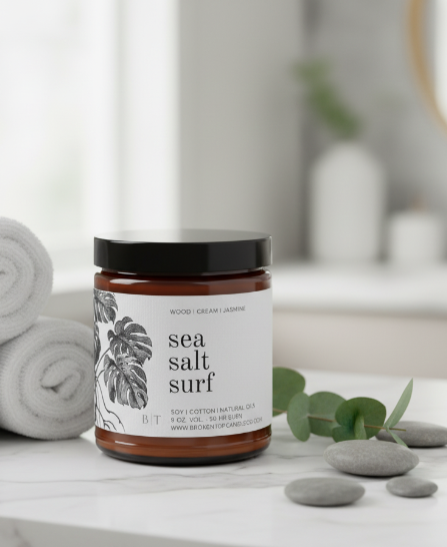 Jar of sea salt surf product on a bathroom counter with towels and stones in the background