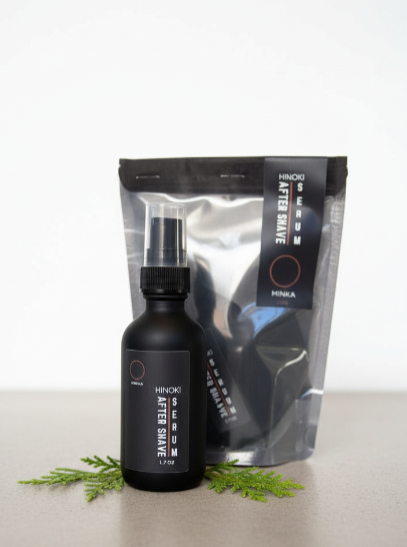 Black bottle of after shave with a silver packaging sleeve on a light gray background