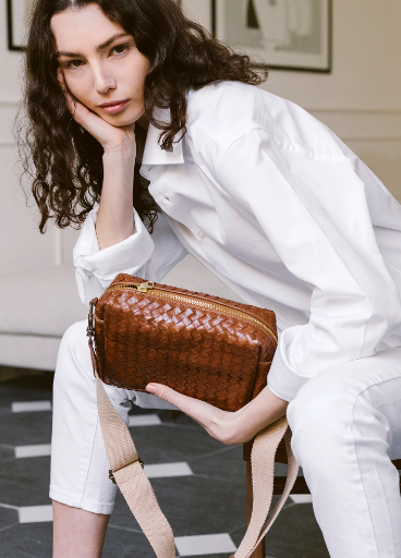 Woman holding a brown woven handbag indoors