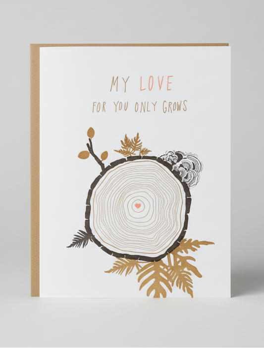 Greeting card with tree ring design and 'My love for you only grows' text on a wooden surface