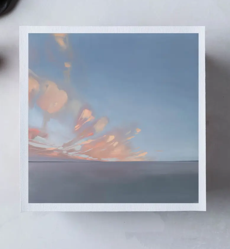 Framed photograph of a sunset or sunrise with a blue sky and fiery orange hues.