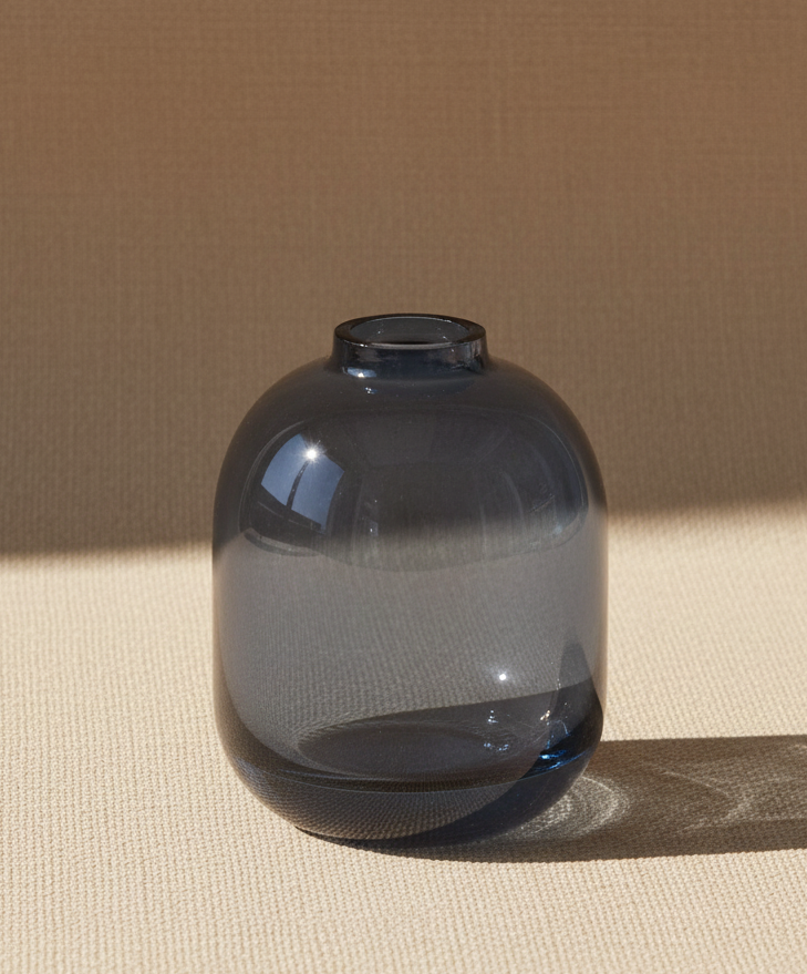 Blue glass vase on a white surface with a blurred background
