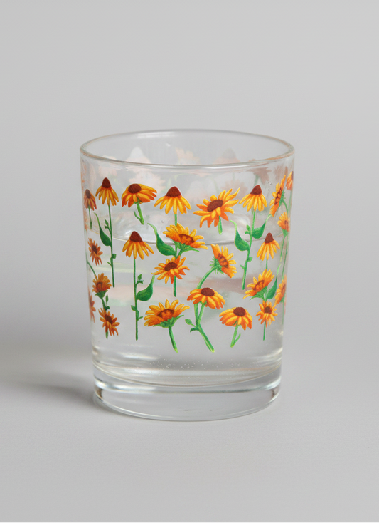 Glass with floral design on a wooden cutting board with lemons